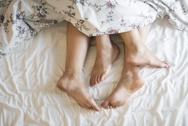 ベッドでの男女の脚の画像
