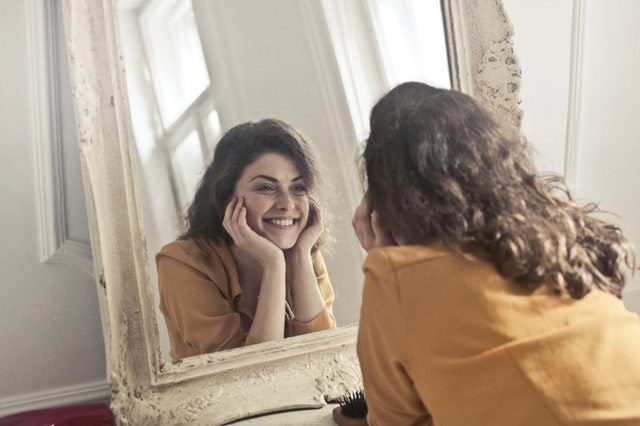 鏡の前でほほ笑む女性の画像