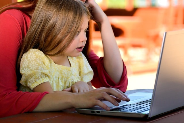 子どもが母親とパソコンに向かう画像